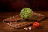 Composition of green cabbage on wooden tablet with knife and vegetables
