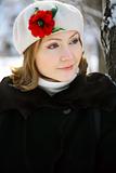 Winter portrait of a young woman in a white cap with a red flower
