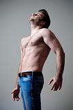 young shirtless musculous man in jeans standing - isolated on gray - isolated on gray