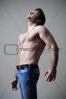 young shirtless musculous man in jeans standing - isolated on gray - isolated on gray