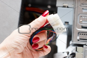 Woman hand assembles computer cable into system unit