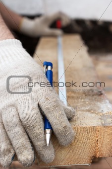 Hands in protective gloves with pen and Metre measure ruler