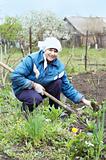 Happy woman farmer digging with spade