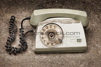Grunge: old broken phone on asphalt background
