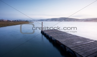 Misty sunrise over river and pier