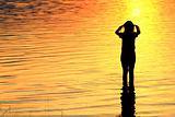 Silhouette of a girl in the water at sunset