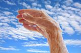 Senior woman's hand over sky