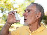 Old man using asthma inhaler outdoors