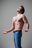 young shirtless musculous man in jeans standing - isolated on gray