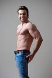 young shirtless musculous man in jeans smiling - isolated on gray