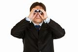 Serious young businessman looking through binoculars
