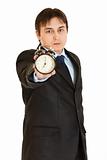 Serious young businessman holding alarm clock in hand
