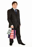 Smiling young businessman holding shopping bags
