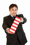 Smiling young businessman giving shopping bag

