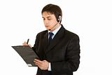 Serious young businessman with headset and clipboard
