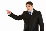 Shocked young businessman pointing  finger in corner
