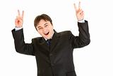 Laughing young businessman showing victory gesture
