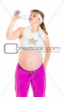 Pregnant woman drinking water from bottle after exercising
