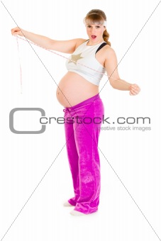 Shocked beautiful pregnant woman  holding measure tape
