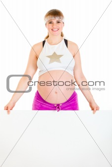 Smiling beautiful pregnant woman holding blank billboard
