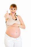 Happy pregnant woman touching her belly and showing  thumbs up gesture
