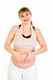 Smiling pregnant woman making heart with her hands on belly
