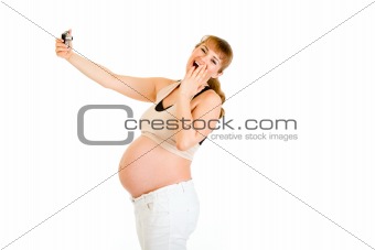 Laughing pregnant woman photographing herself
