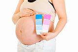 Pregnant woman holding colour paint samples. Close-up.
