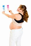 Smiling pregnant woman holding color paint samples

