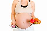 Pregnant woman holding pills and fruits. Close-up.
