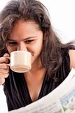 Smilling indian teen reading newspaper with coffee