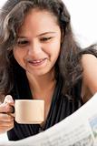 Smilling indian teen reading newspaper with coffee