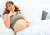 Dreams beautiful pregnant woman sitting on sofa and holding her belly
