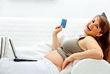 Happy beautiful pregnant woman using credit card to shop from  internet
