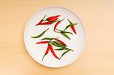Hot peppers in the plate on wooden table