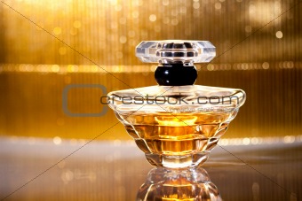 Bottle of perfume with reflection on gold