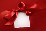 Satin bow and white card for gift on red 
