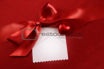 Satin bow and white card for gift on red 