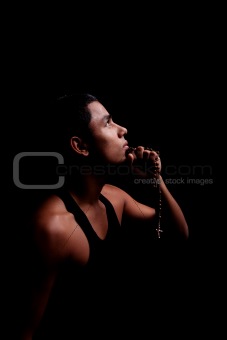 young latin men with a crucifix on hands, isolated on black, studio shot