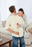 Hasty woman looking at rose hidden behind her boyfriend's back