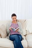 Attentive woman reading a book on the sofa