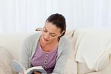 Passionate woman reading a fiction sitting on the sofa