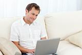 Cute man surfing on the web on the sofa