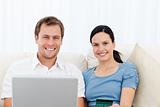 Relaxed couple with laptop and credit card sitting on the sofa