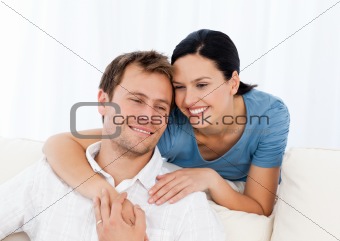 Lovely woman hugging her boyfriend while relaxing on the sofa