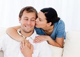 Lovely woman kissing her boyfriend while relaxing on the sofa