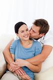 Happy man kissing his girlfriend while relaxing on the sofa