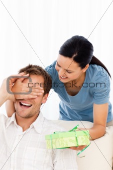 Happy woman giving a present to his boyfriend while hiding his eyes