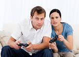 Concentrated couple playing video games together on the sofa