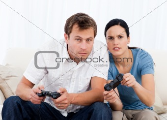 Concentrated couple playing video games together on the sofa